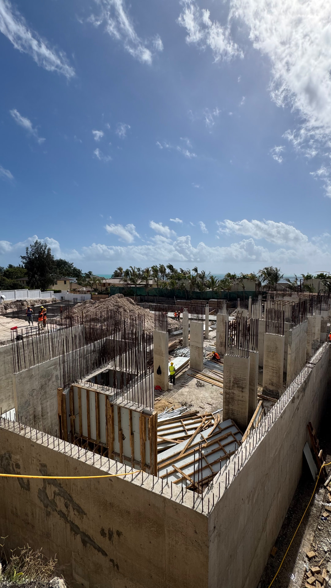 Samawa Beach Resort construction — rebar columns and formwork rising with the Indian Ocean beyond